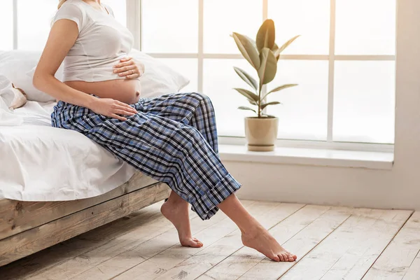 Junge schwangere Frau sitzt im Schlafzimmer — Stockfoto