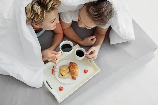 침실에서 아침 식사를 즐기는 행복 한 연인 — 스톡 사진