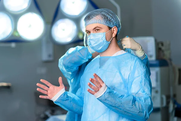 Interested doctor dressing in protective uniform — Stock Photo, Image