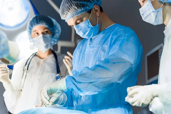 Ernsthafte medizinische Fachkräfte, die Person operieren — Stockfoto