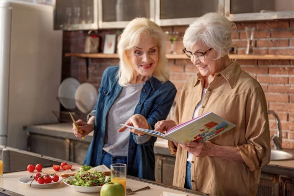 Веселі старі жінки читають на кухні — стокове фото