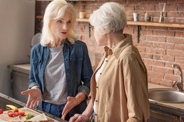 Dos viejas amigas comunicándose en la sala de cocina —  Fotos de Stock