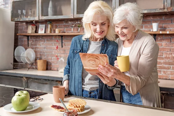 Старі жінки друзі дивляться фотографії разом — стокове фото
