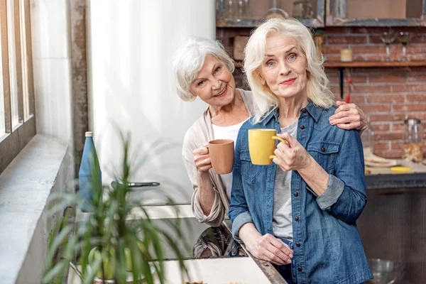 Felices mujeres mayores relajándose con una taza de bebida caliente — Foto de Stock
