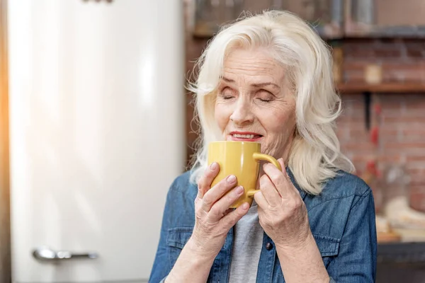 Happy mature lady relaxing with hot beverage — Stock Photo, Image