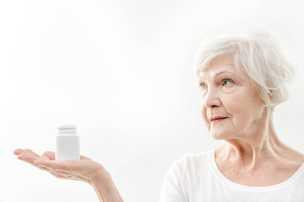 Здоровая пожилая женщина показывает таблетки
