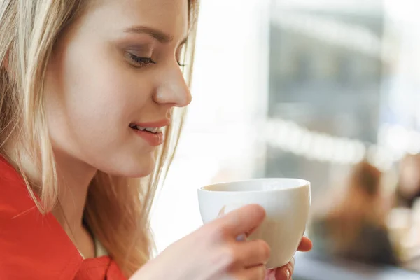 Söpö blondi nainen juo kahvia kahvilassa — kuvapankkivalokuva