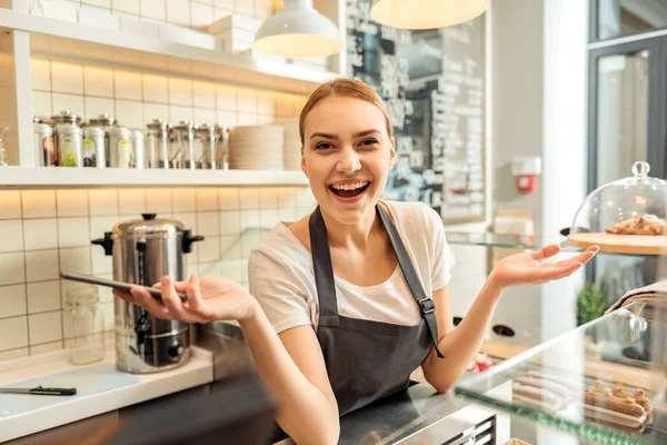 Excited saleswoman using mobile phone in cafeteria