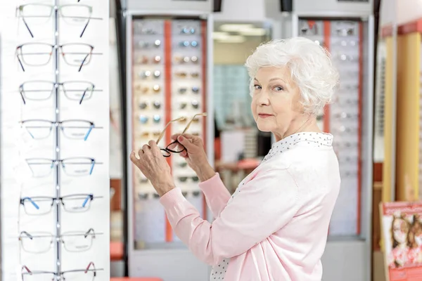 Nyfiken gammal dam att hålla glasögon — Stockfoto