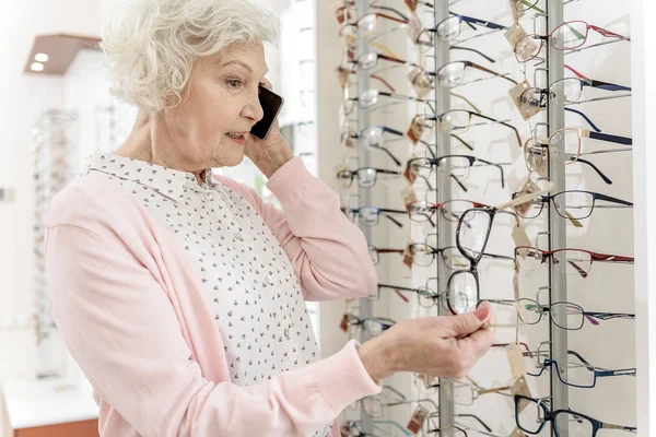 Mujer mayor ocupada eligiendo gafas —  Fotos de Stock