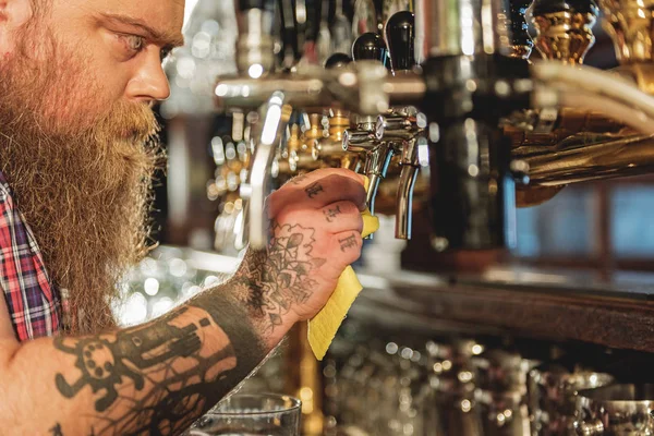 Calm bearded male washing beer tap