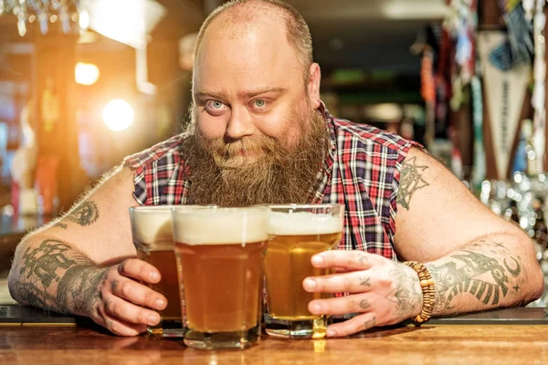 Hombre barbudo alegre colocando vasos de cerveza — Foto de Stock