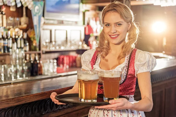 Mujer alegre sosteniendo bandeja con vasos de cerveza — Foto de Stock