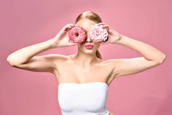Молодая женщина держит два пончика — стоковое фото