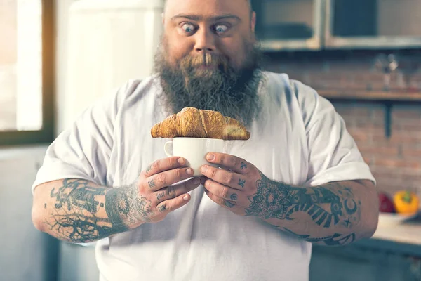 Fome masculino gordo olhando para croissant com apetite — Fotografia de Stock
