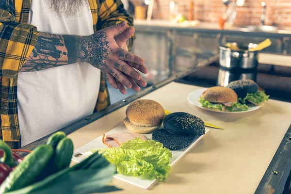 Fat Man koken hamburgers in keuken — Stockfoto