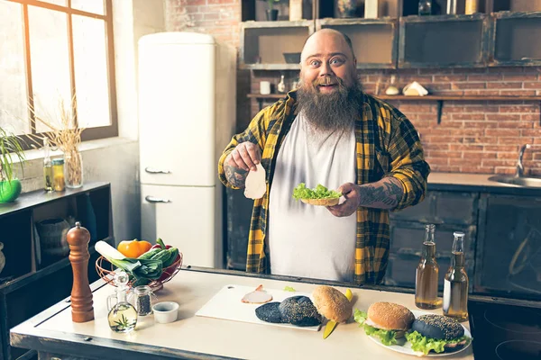 Wesoły facet gruby, ciesząc się przygotowanie burger — Zdjęcie stockowe