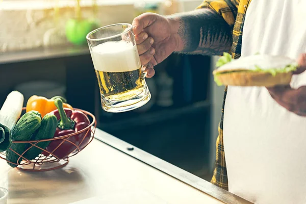 Dikke man drinken van alcohol met Hamburger — Stockfoto