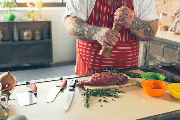 Thick guy peppering meat before cooking