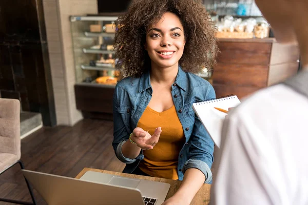 Femme heureuse racontant avec travailleur dans un café — Photo