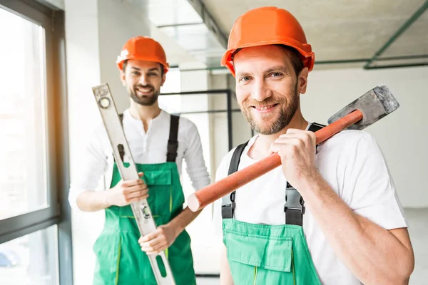 Felices contratistas sonrientes manteniendo herramientas —  Fotos de Stock