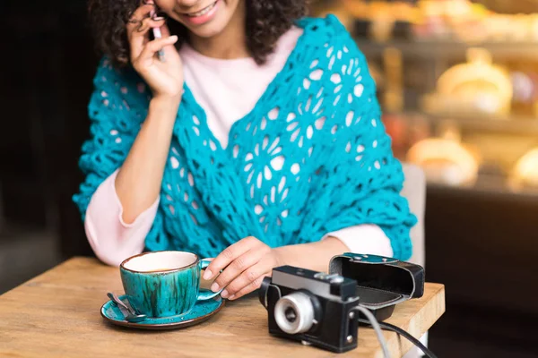 Cheerful mulatto girl talking on phone in cafe