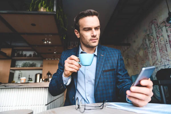 Спокойный бизнесмен смотрит на мобильный телефон — стоковое фото