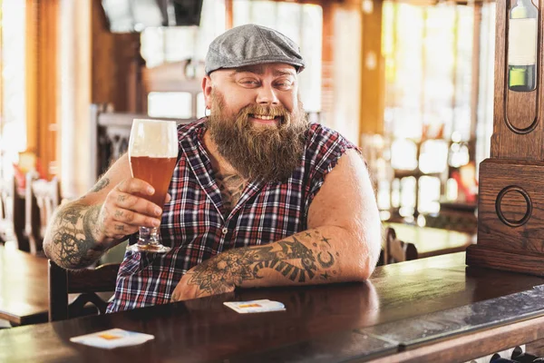 Позитивный бородатый мужчина пьет напиток в пабе — стоковое фото