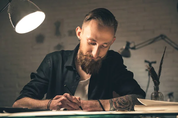Счастливый бородатый мужчина создает картины за столом — стоковое фото