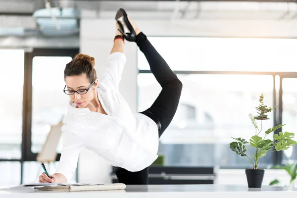 Исходящий секретарь делает гимнастические упражнения в офисе — стоковое фото