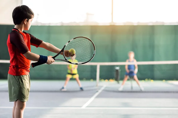Niños alegres jugando tenis en la cancha —  Fotos de Stock