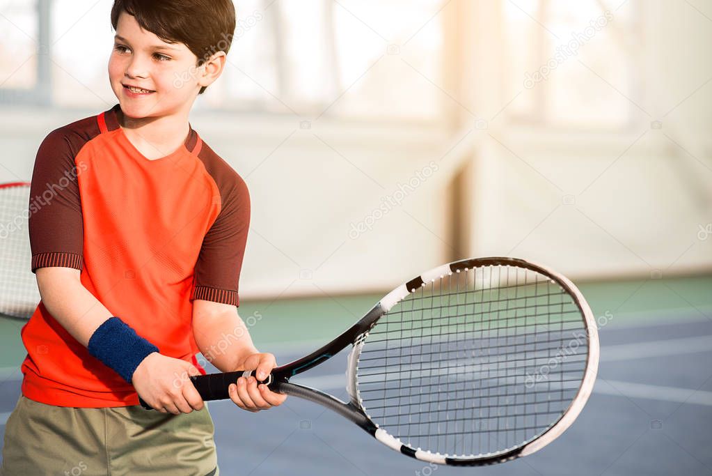 Excited male child having fun on tennis court