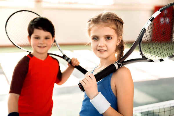 Niños emocionados jugando al tenis en la cancha —  Fotos de Stock