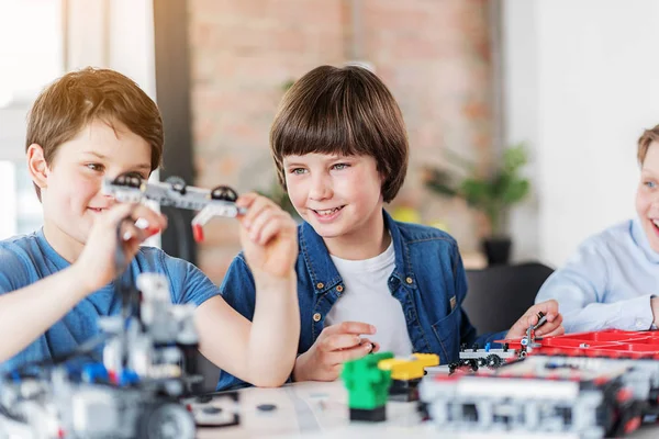 Interesserte smilende barn som lager teknisk leketøy – stockfoto
