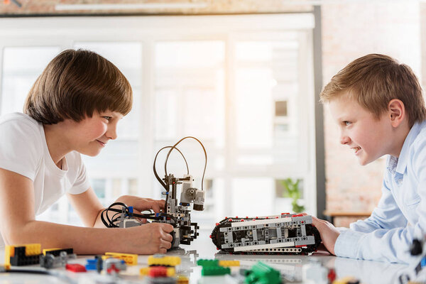 Cheerful male children playing with robotics
