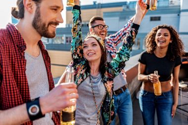 Neşeli genç erkek ve kadınların çatıda bira içmek