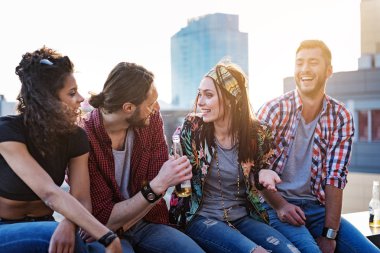 Çatı katındaki terasta dışarı asılı neşeli gençler