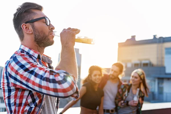 Веселый парень наслаждается алкогольным напитком на террасе на крыше — стоковое фото