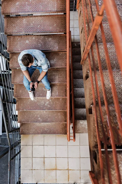 Chico con estilo usando smartphone en las escaleras — Foto de Stock