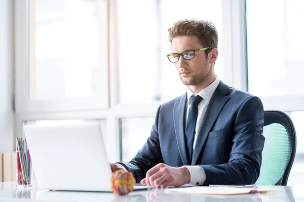 Tranquil empleado positivo en traje está escribiendo en el cuaderno — Foto de Stock