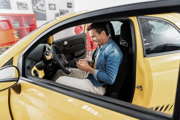 Hombre saliente escribiendo sms por teléfono en el coche — Foto de Stock