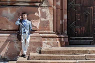 Mutlu gülümseyen erkek kişi konuşmak için Smartphone kullanarak