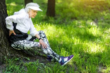 Tired old woman resting after strong training outdoors clipart