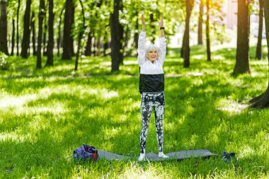 Üst düzey Bayan açık havada yeşil çimenlerin üzerinde yapıyor Düldül