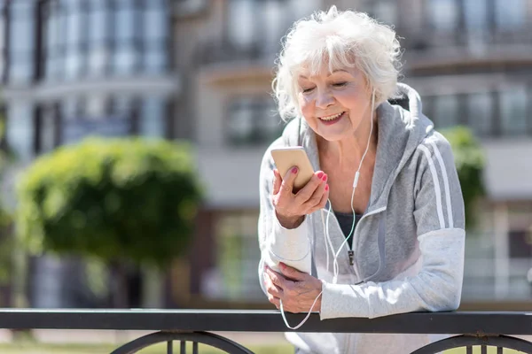 Веселая старая спортивная женщина слушает музыку через наушники — стоковое фото