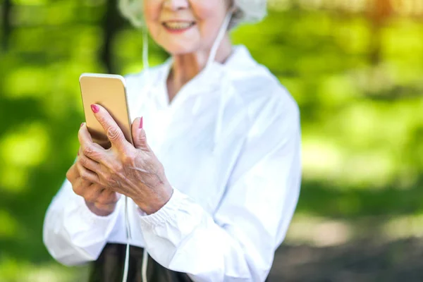 Mobiltelefon használata közben gyakorlás kint, boldog idős hölgy — Stock Fotó
