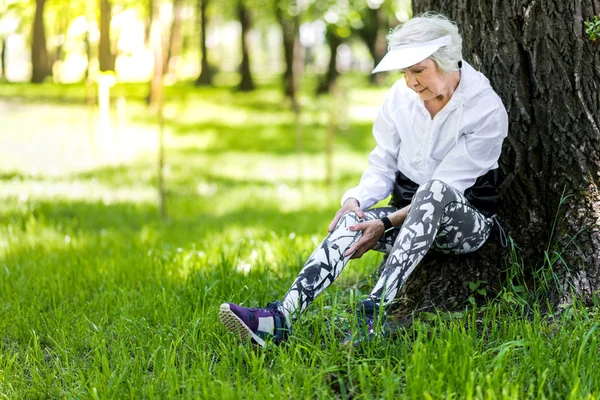 Серьезная старуха отдыхает после тренировки в зеленом лесу — стоковое фото