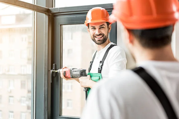 Construtor sorridente feliz trabalhando com puncher — Fotografia de Stock