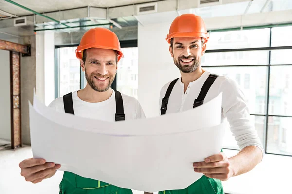 Hilarantes constructores sonrientes guardando papeles — Foto de Stock