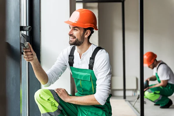 Fröhlich lächelnder Bauarbeiter färbt Oberfläche — Stockfoto